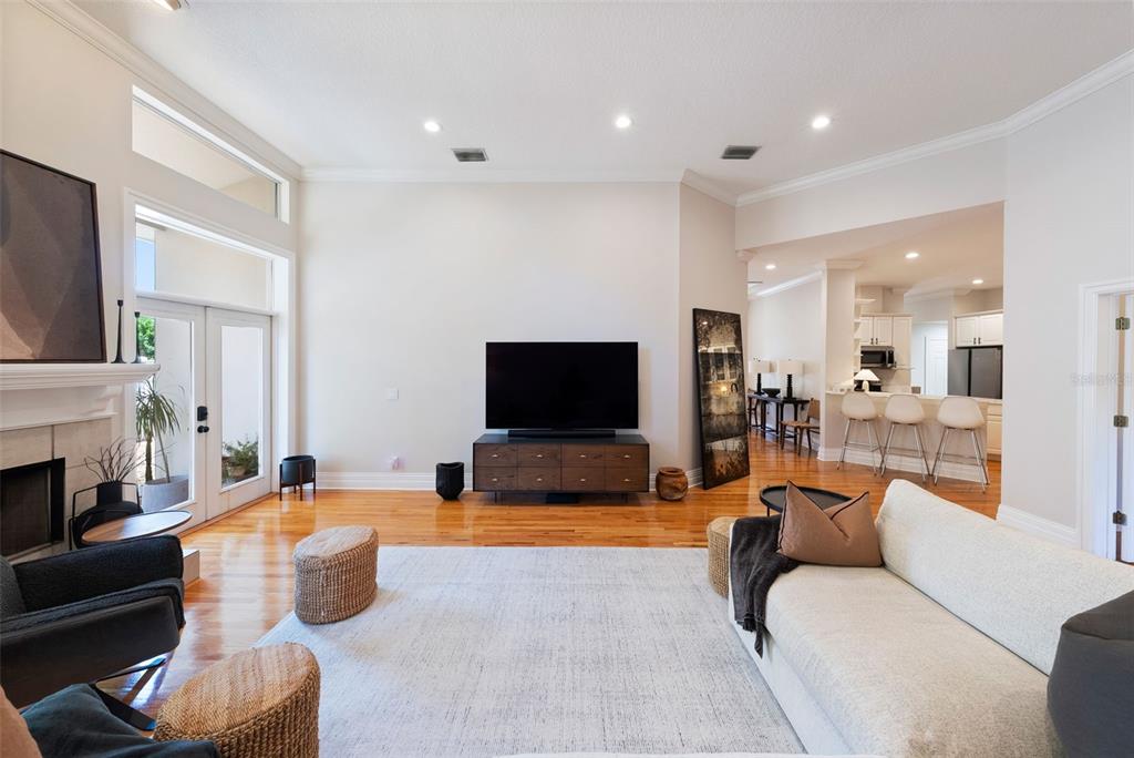 A living room with hardwood floors, a television on a console, and an adjacent kitchen — 2504 W TENNESSEE AVENUE UNIT A, TAMPA, FL