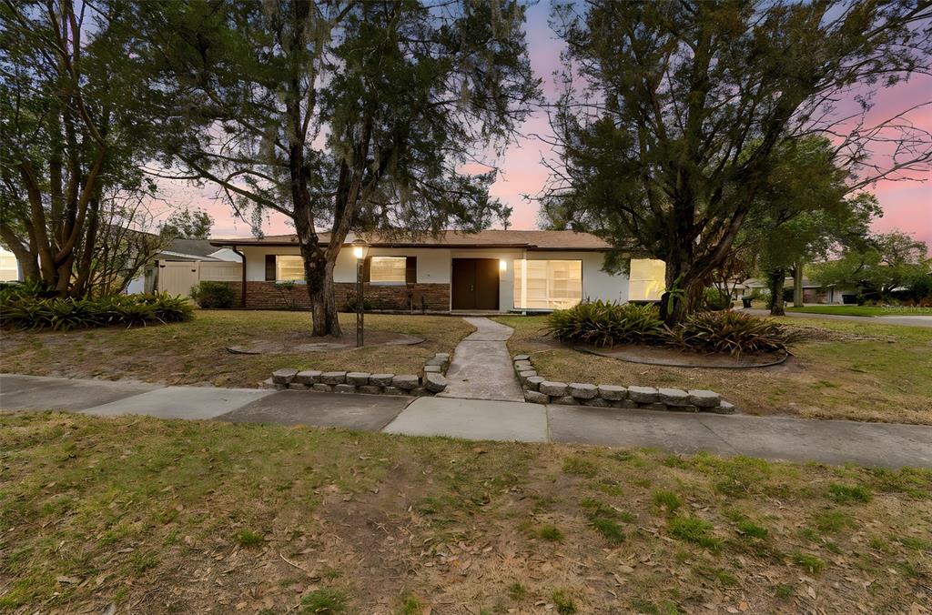 A single-story house with a brick and white exterior, a walkway, and large trees — 2708 LION HEART ROAD, WINTER PARK, FL