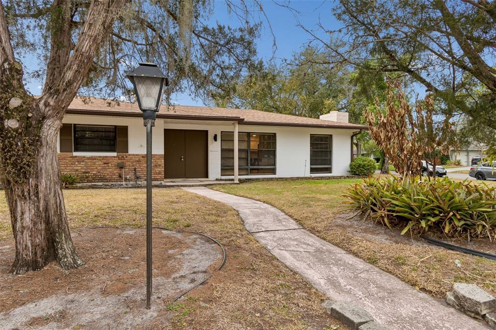 A single-story house with a brick and white exterior sits behind a large front yard — 2708 LION HEART ROAD, WINTER PARK, FL