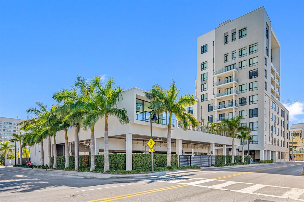 A modern multi-story apartment building with a parking garage base and palm trees outside — 5 N OSCEOLA AVENUE UNIT 508, CLEARWATER, FL