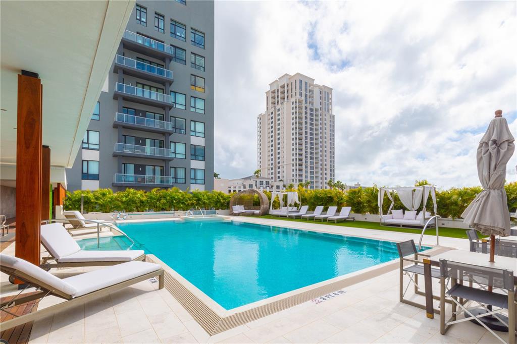 A swimming pool with lounge chairs and cabanas sits between two tall apartment buildings — 5 N OSCEOLA AVENUE UNIT 508, CLEARWATER, FL