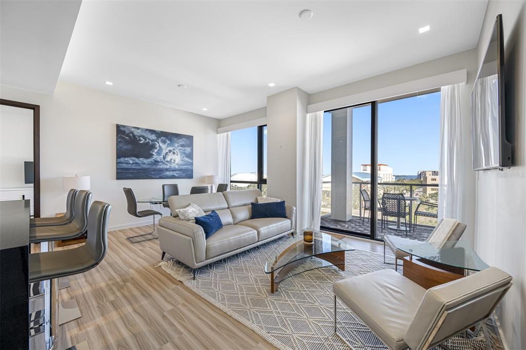 A modern living room features a grey sofa, glass coffee table, and a balcony view — 5 N OSCEOLA AVENUE UNIT 508, CLEARWATER, FL
