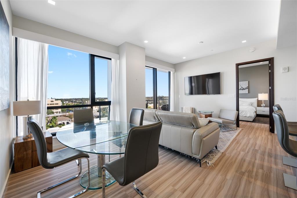 A modern living and dining area with a glass table, leather chairs, and floor-to-ceiling windows — 5 N OSCEOLA AVENUE UNIT 508, CLEARWATER, FL