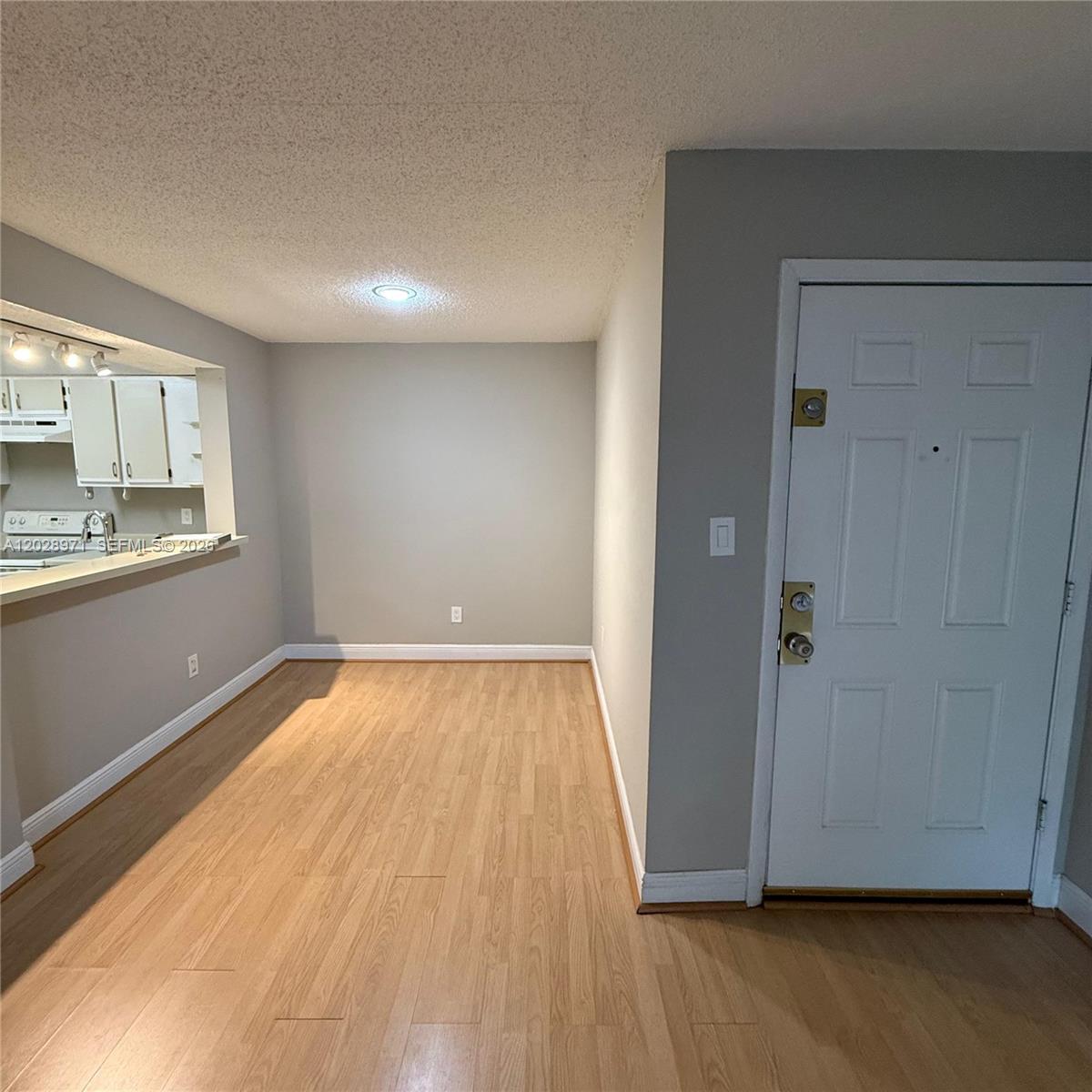 An interior view shows a dining area with light wood flooring, gray walls, and a kitchen pass-through — POMPANO BEACH, FL