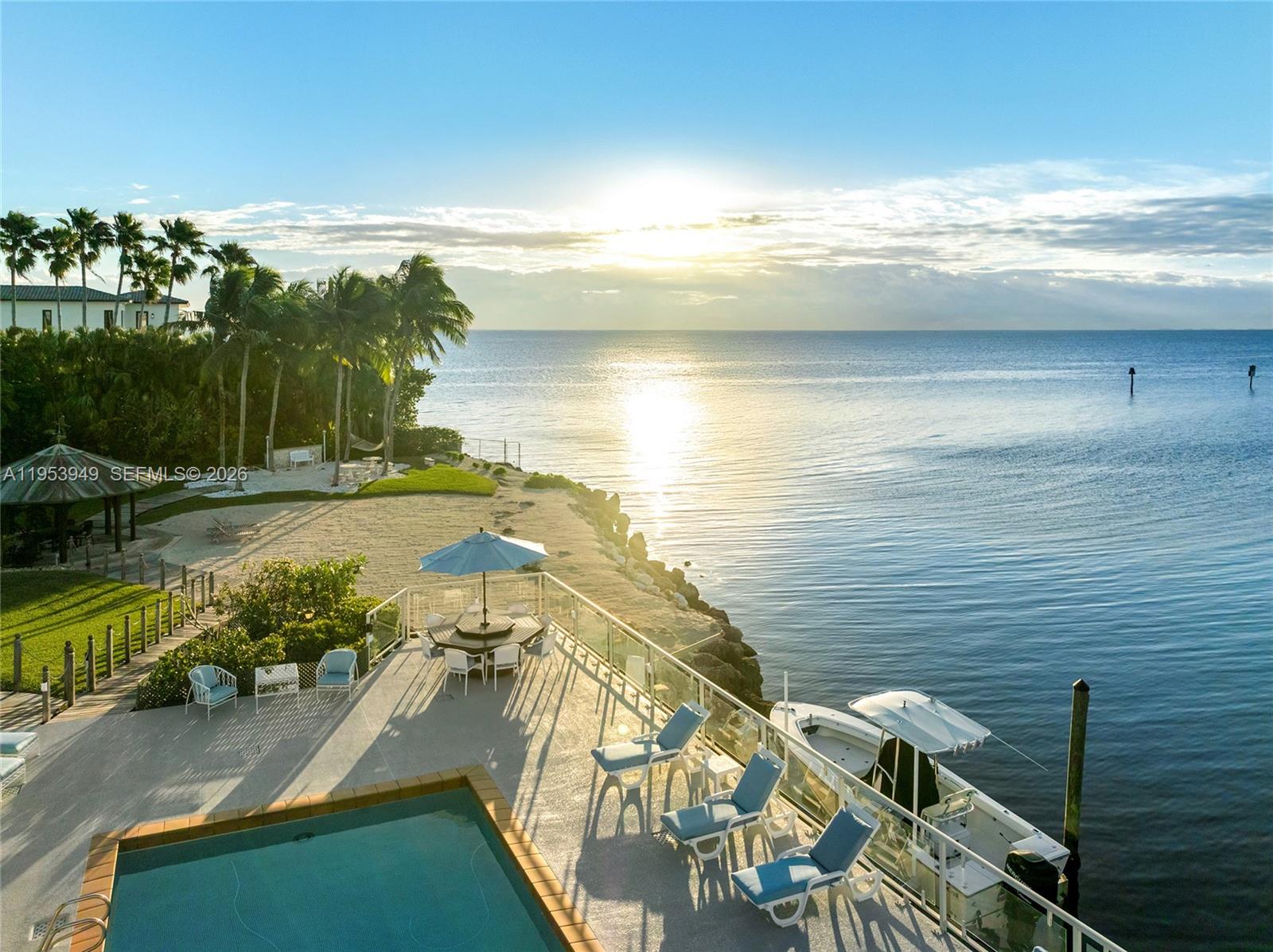 A swimming pool deck features lounge chairs, a dining set, and a dolphin statue at sunset — 720 Lugo Ave, Coral Gables FL 33156, CORAL GABLES, FL
