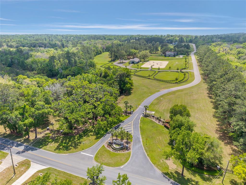 An aerial view shows a paved driveway leading to a gated entrance and equestrian property — TBD SW 144 COURT ROAD, OCALA, FL