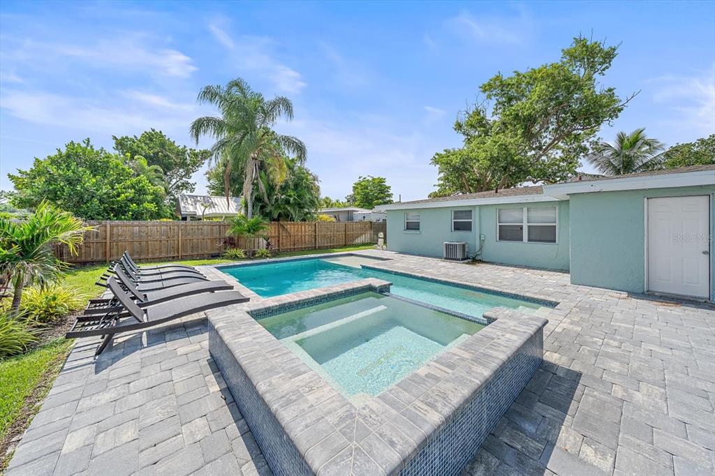A backyard features a swimming pool, a raised hot tub, and lounge chairs on pavers — 2135 LEE LANE, SARASOTA, FL