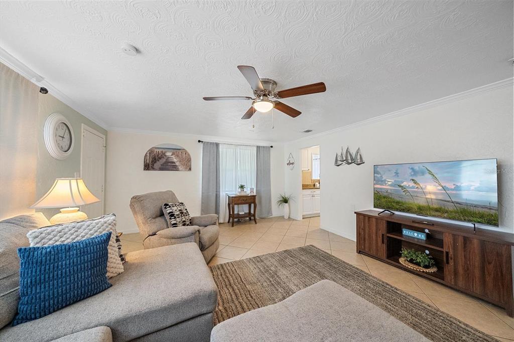 A living room features tile floors, a ceiling fan, a sectional sofa, and a television — 2135 LEE LANE, SARASOTA, FL