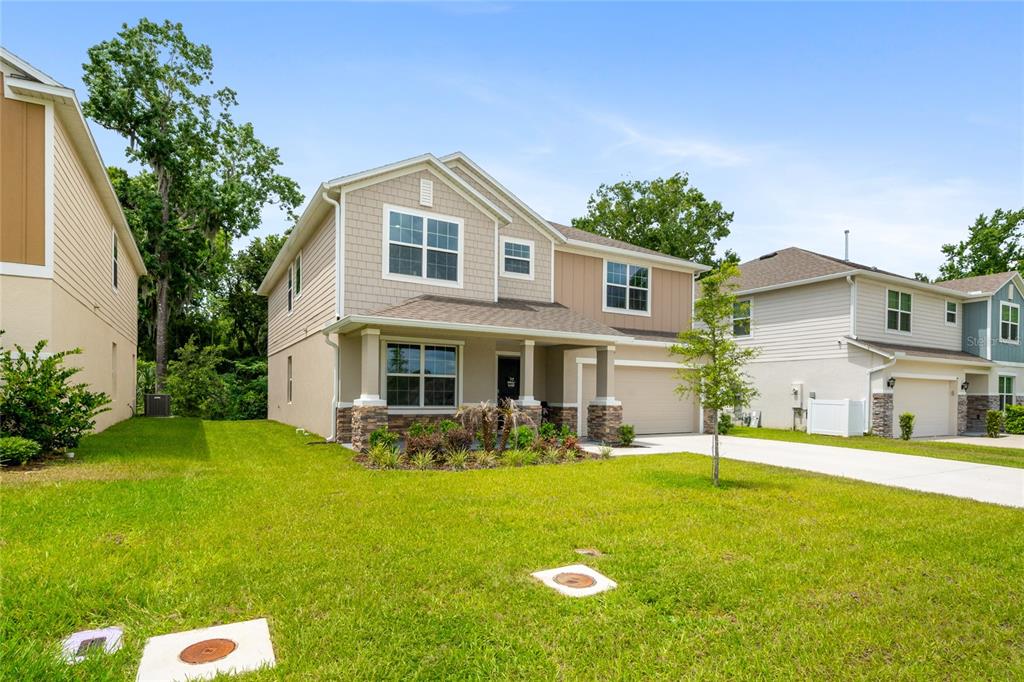 A two-story suburban house with tan siding, stone accents, and a front-facing garage — 1137 BRADFORD RIDGE DRIVE, LEESBURG, FL