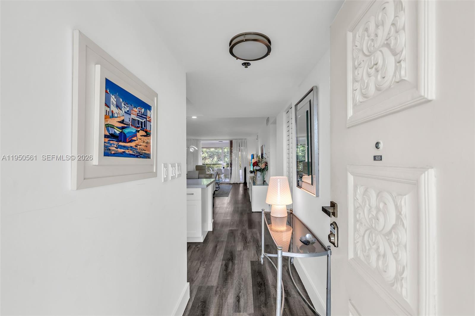 A bright entryway leads into a living area with wood-look flooring and white walls — 3910 Inverrary Blvd # B, Lauderhill FL 33319, LAUDERHILL, FL