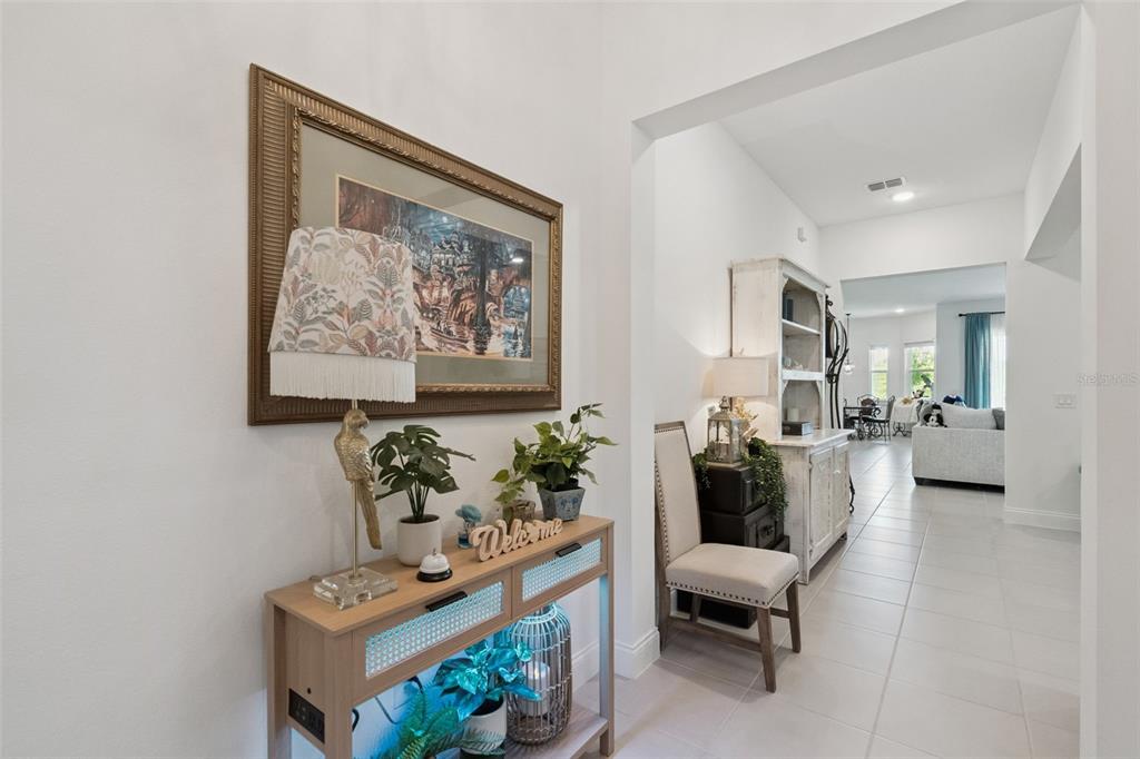 A bright entryway features a console table, a framed picture, and a view into a living area — 15652 GENTLE RAIN DRIVE, WINTER GARDEN, FL