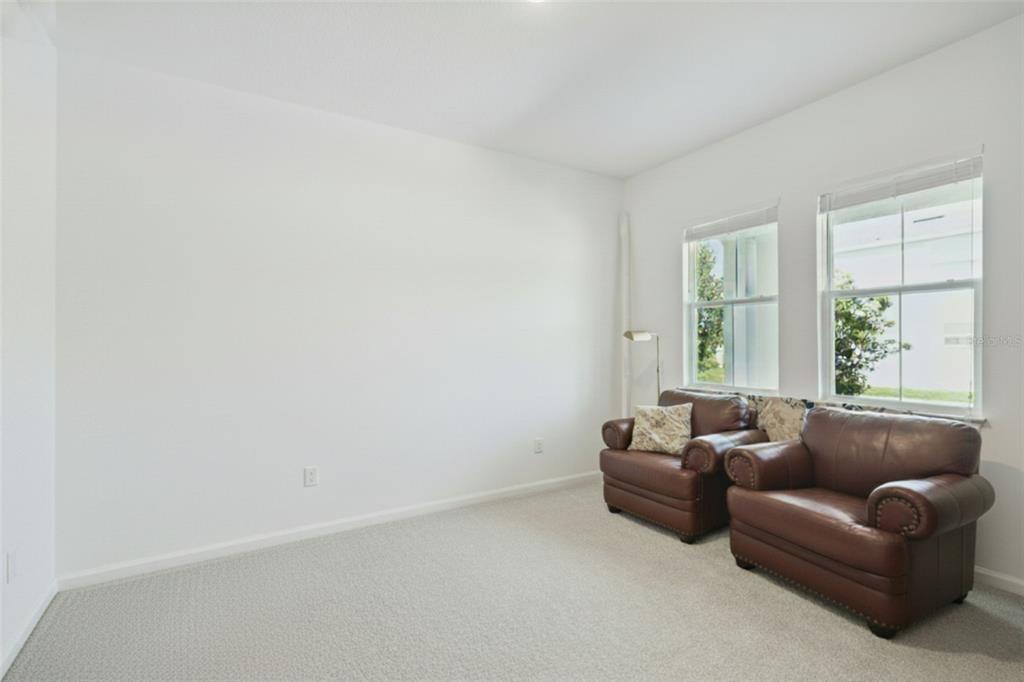 A room with white walls, beige carpeting, and two brown leather armchairs near two windows — 15652 GENTLE RAIN DRIVE, WINTER GARDEN, FL