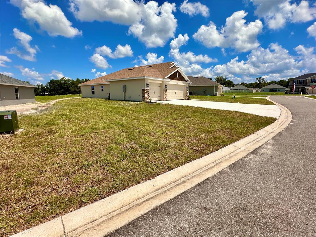 A single-story house with a tan exterior and a two-car garage sits on a corner lot — 4493 NE 31ST PLACE, OCALA, FL