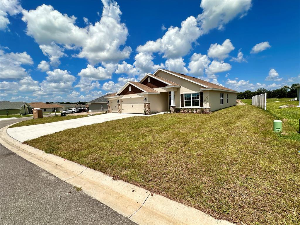 A single-story house with a two-car garage and a beige exterior sits on a lawn — 4493 NE 31ST PLACE, OCALA, FL