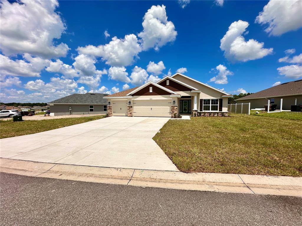 A single-story suburban house with a beige exterior, brown gables, and a concrete driveway — 4493 NE 31ST PLACE, OCALA, FL