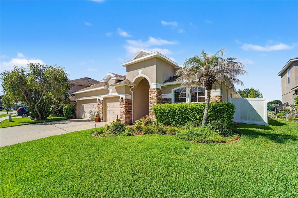 A single-story house with a two-car garage, stone accents, and a palm tree in front — 27236 HOLLYBROOK TRAIL, WESLEY CHAPEL, FL