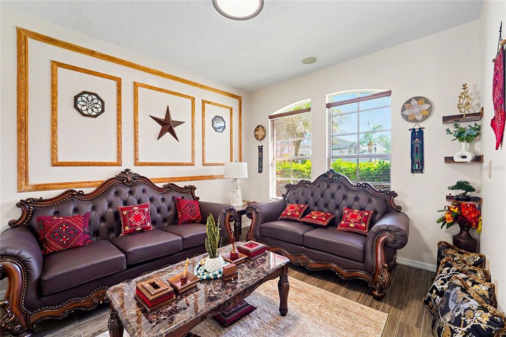 A living room features two dark leather sofas, a marble coffee table, and wall molding — 27236 HOLLYBROOK TRAIL, WESLEY CHAPEL, FL