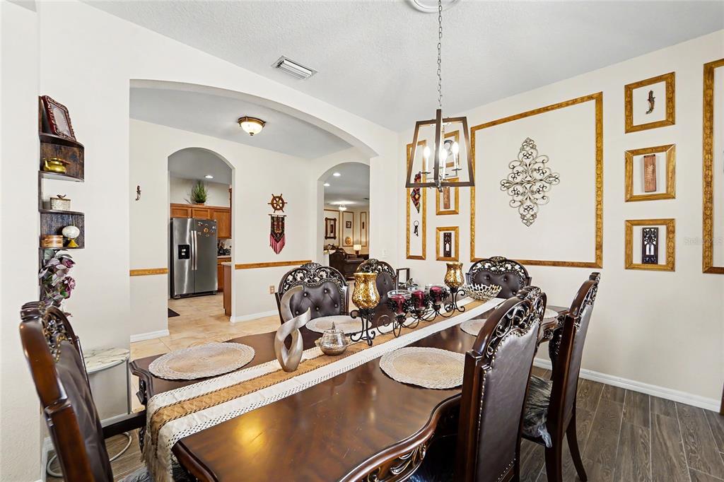 A formal dining room features a dark wood table, ornate chairs, and decorative wall moldings — 27236 HOLLYBROOK TRAIL, WESLEY CHAPEL, FL