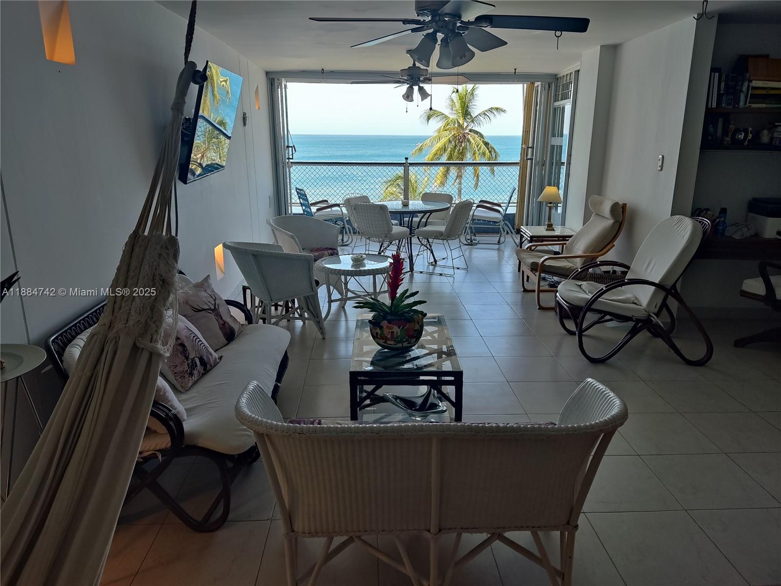 A living room with wicker furniture and a hammock overlooks the ocean through open doors — Carrera 1a # 5-06, SA 130001, SA