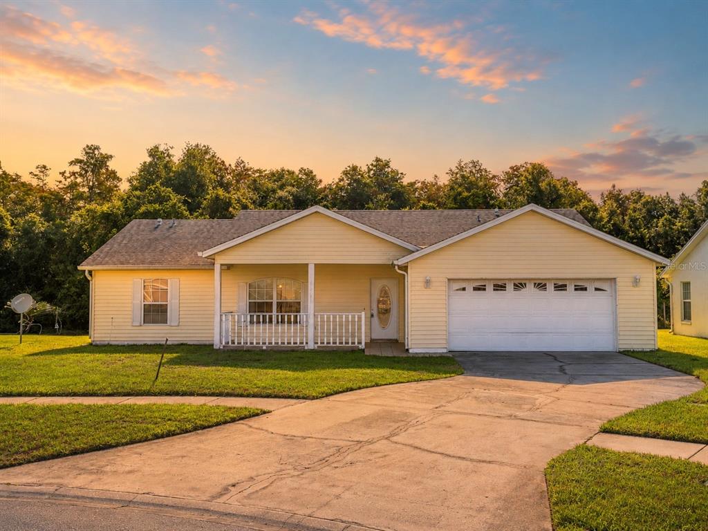 A yellow single-story house with a white garage door and a front porch at sunset — 3837 SPRINGLAKE VILLAGE COURT, KISSIMMEE, FL