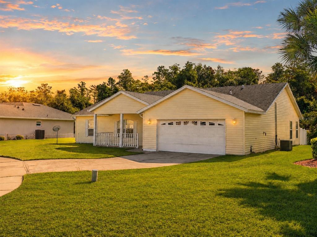 A yellow single-story house with a white garage door and a front porch at sunset — 3837 SPRINGLAKE VILLAGE COURT, KISSIMMEE, FL
