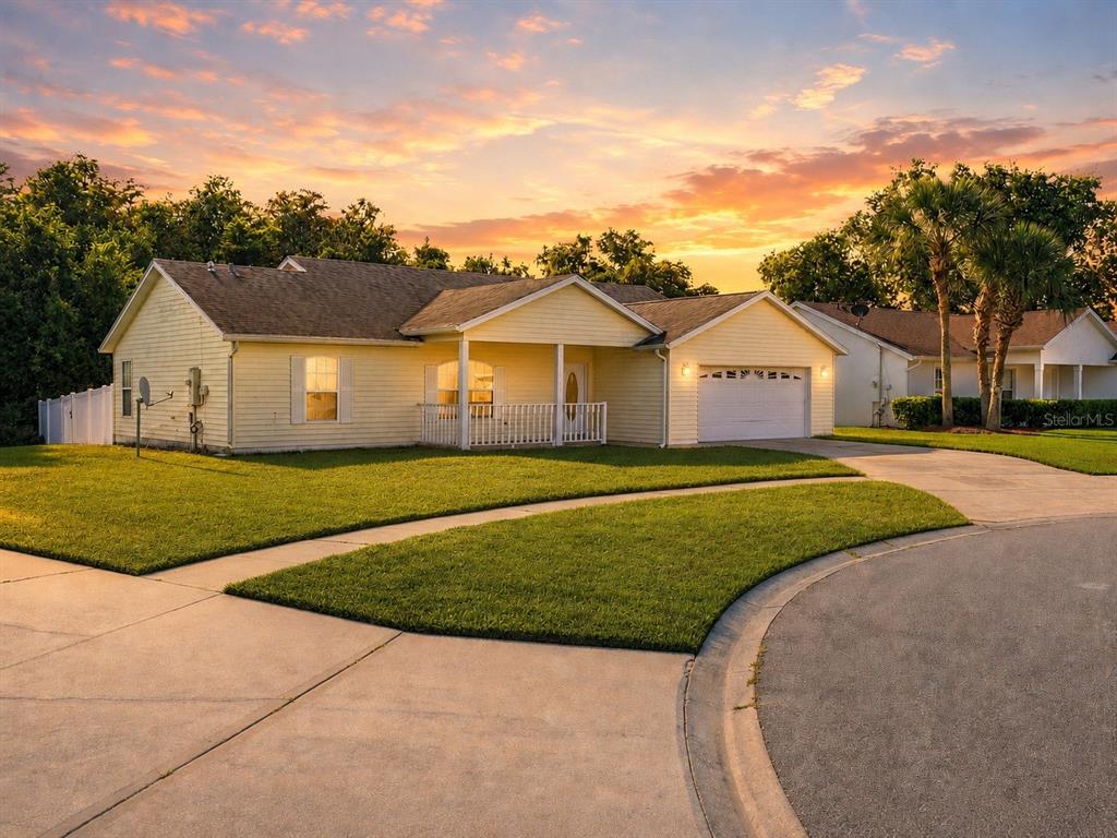 A yellow single-story house with a white garage and a front porch at sunset — 3837 SPRINGLAKE VILLAGE COURT, KISSIMMEE, FL