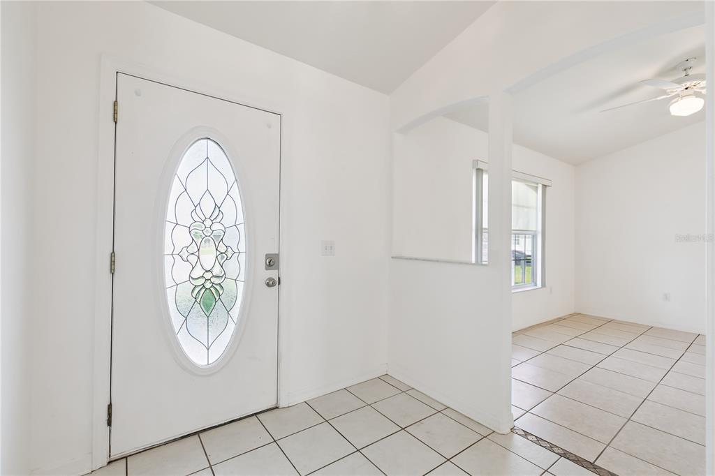 An entryway with white walls, tiled floors, and a front door with a decorative glass insert — 3837 SPRINGLAKE VILLAGE COURT, KISSIMMEE, FL