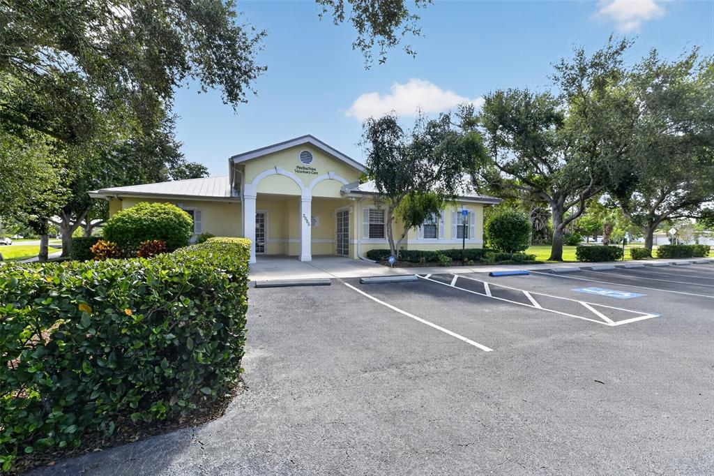 A yellow, single-story veterinary clinic building sits behind a parking lot with mature trees — 2555 PINELLAS POINT DRIVE S, ST PETERSBURG, FL