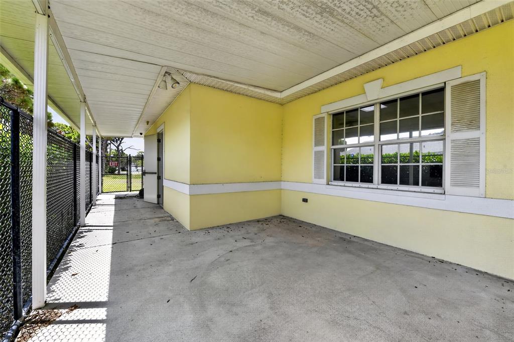 A covered concrete patio features yellow exterior walls, a large window, and a chain-link fence — 2555 PINELLAS POINT DRIVE S, ST PETERSBURG, FL