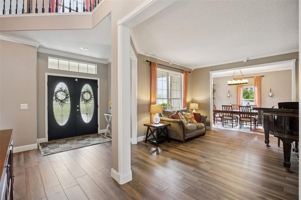 An entryway features a dark double door, a console table, a mirror, and wood flooring — 1267 OAKFORD PLACE, OVIEDO, FL