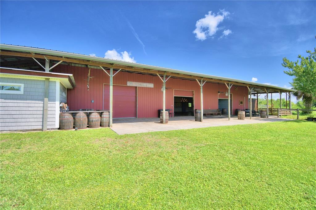 A red metal barn with a covered concrete patio and several wooden barrels outside — 5713 LUCERNE PARK ROAD, WINTER HAVEN, FL