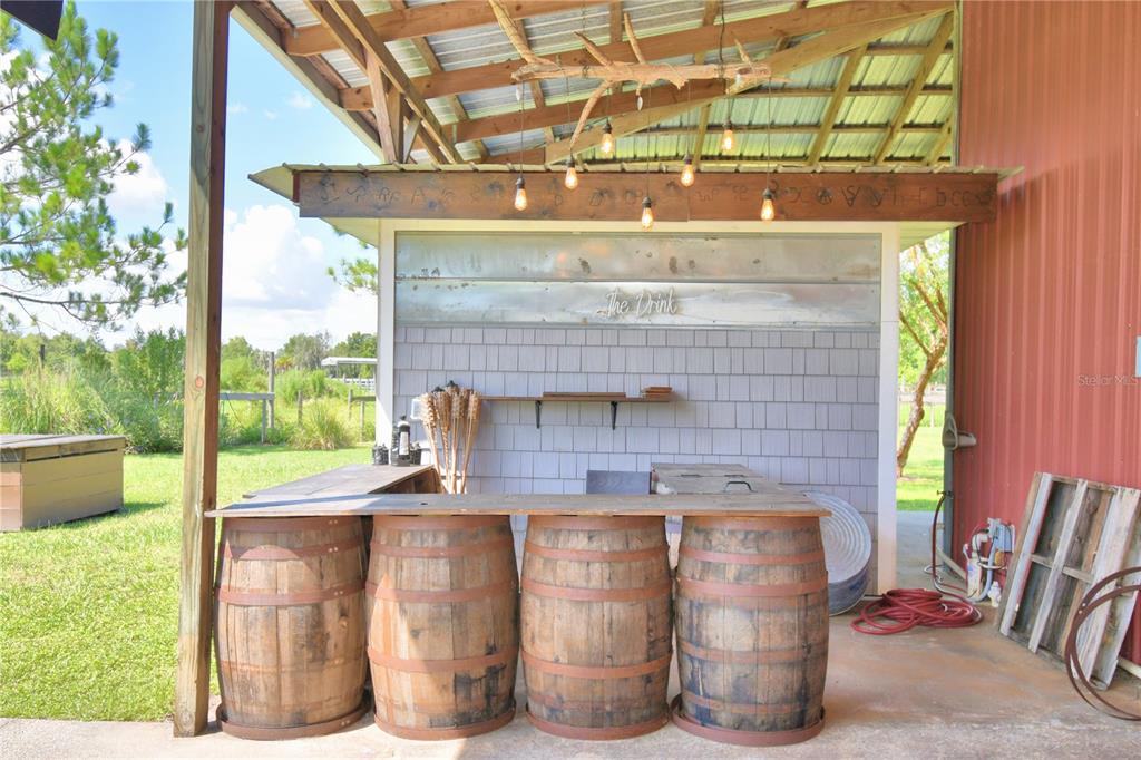 An outdoor bar features a wooden countertop supported by four barrels under a covered patio — 5713 LUCERNE PARK ROAD, WINTER HAVEN, FL