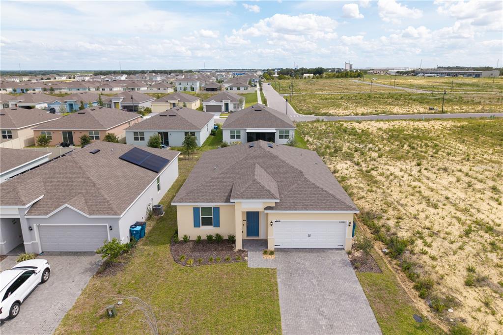 An aerial view shows a single-story suburban house with a tan exterior and paved driveway — 740 RICHMOND ESTATE AVENUE, HAINES CITY, FL