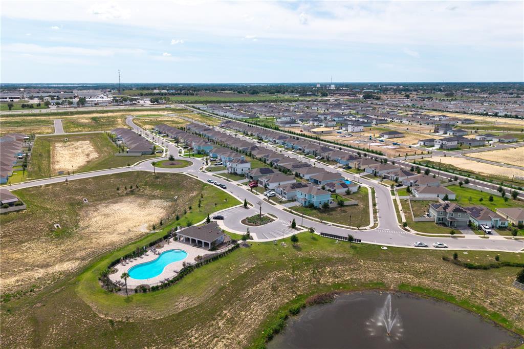 An aerial view shows a suburban neighborhood with a community pool, pond, and houses — 740 RICHMOND ESTATE AVENUE, HAINES CITY, FL