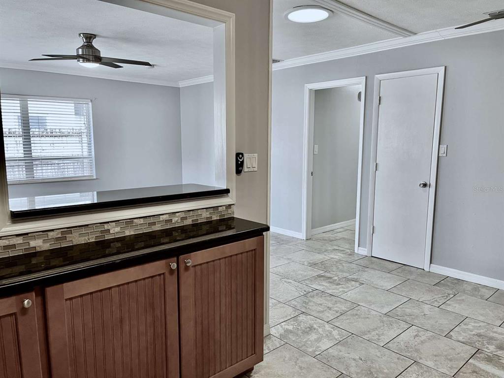 A kitchen pass-through window overlooks a living area with tiled floors and a ceiling fan — 116 S RENELLIE DRIVE, TAMPA, FL