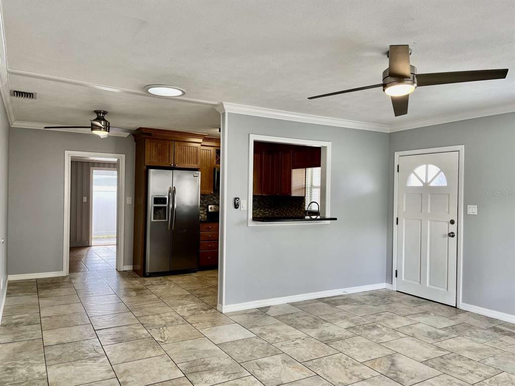 A living room with tile flooring, a ceiling fan, and an opening to the kitchen — 116 S RENELLIE DRIVE, TAMPA, FL