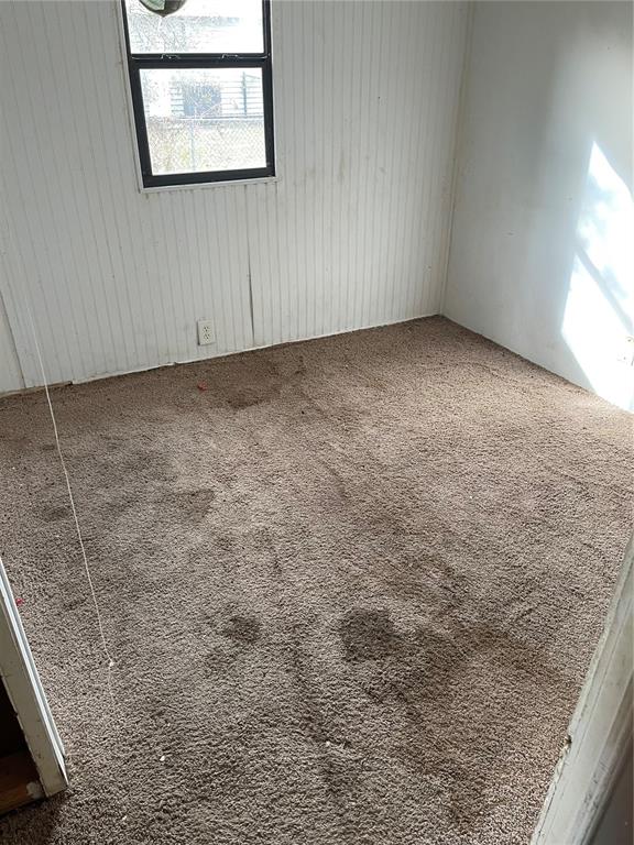 A small, empty bedroom features white vertical-paneled walls, a single window, and brown carpeting — 16148 BOCA RATON STREET, BROOKSVILLE, FL