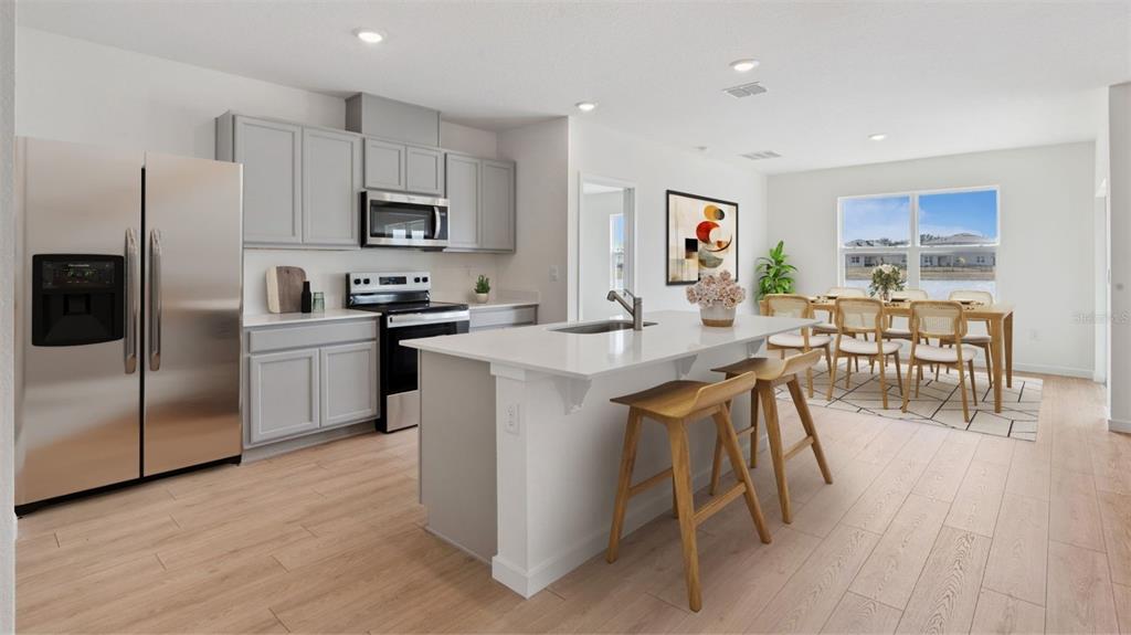 A modern kitchen features light gray cabinets, stainless steel appliances, and a central island — 1901 DEEP LAKE CIRCLE, NEW SMYRNA BEACH, FL