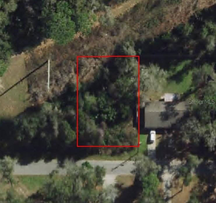 An aerial view shows a rectangular, tree-covered vacant lot outlined in red next to a house — 4935 S ROMANS AVENUE, INVERNESS, FL