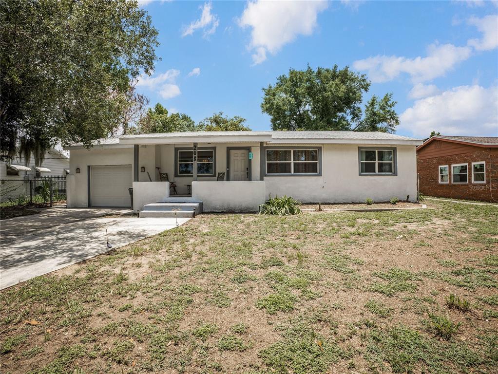 A single-story house with a white exterior, a front porch, and an attached one-car garage — 208 E WINTHROP STREET, AVON PARK, FL