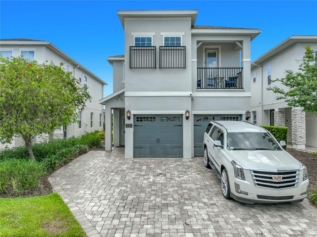 A two-story house with a gray stucco exterior, a paver driveway, and a white SUV — 272 SOUTHFIELD STREET, KISSIMMEE, FL