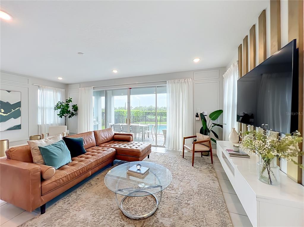 A living room features a leather sectional, glass coffee table, and a wall-mounted television — 272 SOUTHFIELD STREET, KISSIMMEE, FL