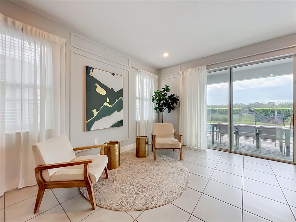 A sunlit sitting area features two cream chairs, gold side tables, and a sliding glass door — 272 SOUTHFIELD STREET, KISSIMMEE, FL