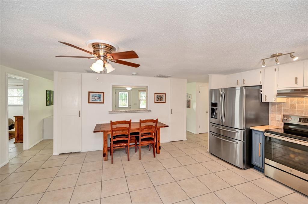 A kitchen with blue cabinets, stainless steel appliances, and tile floors opens to a living area — 9705 W PIMPERNEL LANE, CRYSTAL RIVER, FL