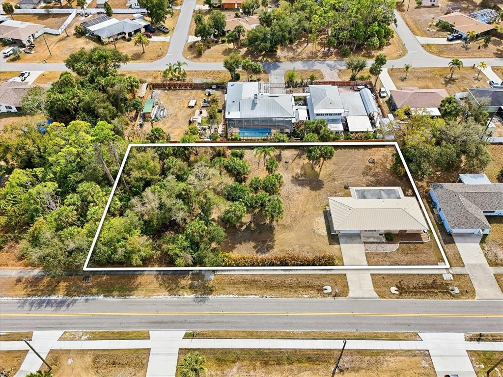 An aerial view shows a residential lot with a house, driveway, and wooded area — 21029 PEACHLAND BOULEVARD, PORT CHARLOTTE, FL