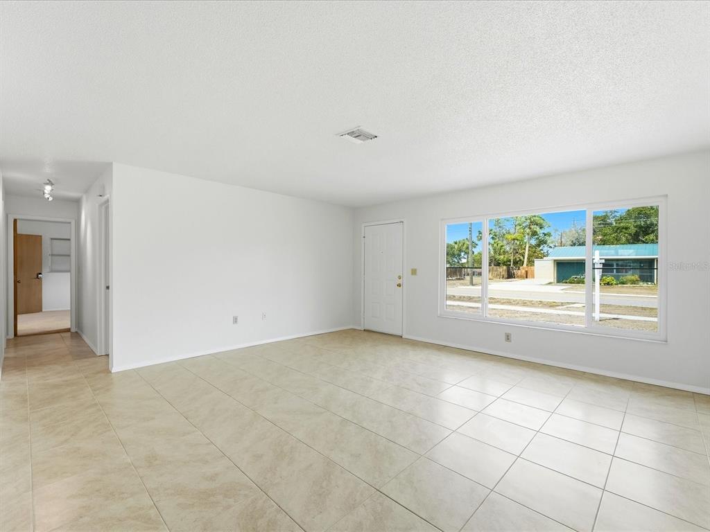 An empty room with white walls, light-colored tile flooring, a front door, and a large window — 21029 PEACHLAND BOULEVARD, PORT CHARLOTTE, FL