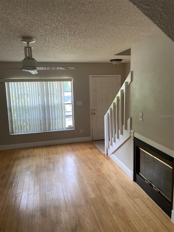 A living room features light wood flooring, a fireplace, a ceiling fan, and a staircase — 130 RHODEN LANE, WINTER SPRINGS, FL