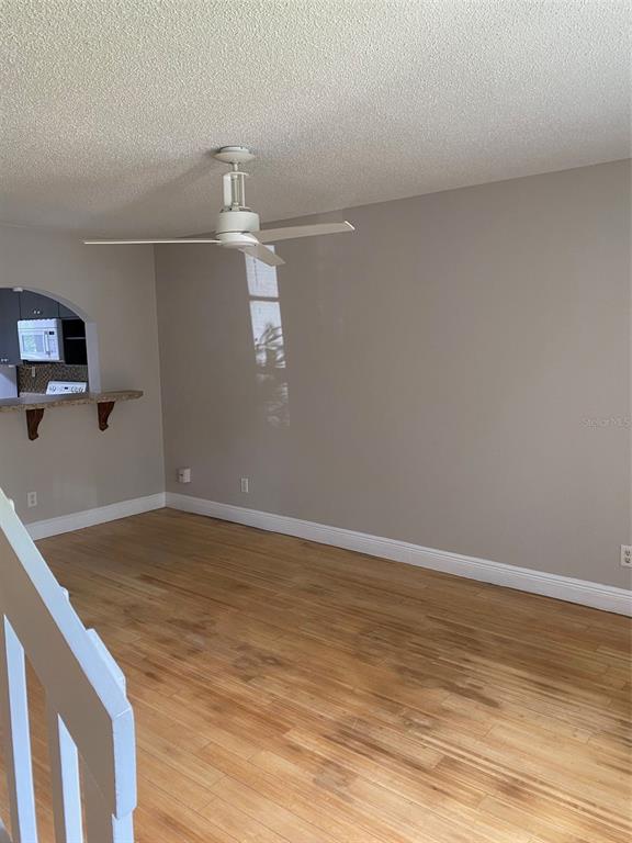 An empty living room features light wood flooring, beige walls, and a white ceiling fan — 130 RHODEN LANE, WINTER SPRINGS, FL