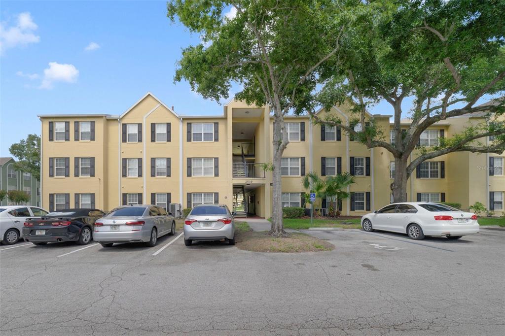 A three-story apartment building with yellow stucco walls and a parking lot in front — 2019 DIXIE BELLE DRIVE UNIT G, ORLANDO, FL
