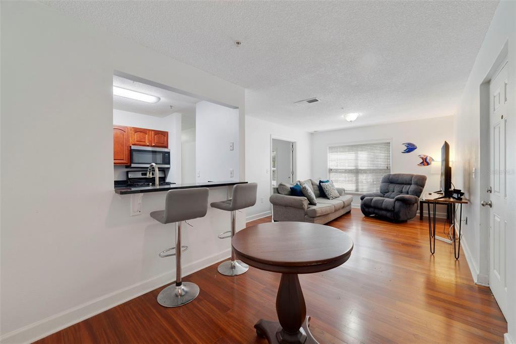 A living room with wood floors, a breakfast bar, and an open kitchen view — 2019 DIXIE BELLE DRIVE UNIT G, ORLANDO, FL